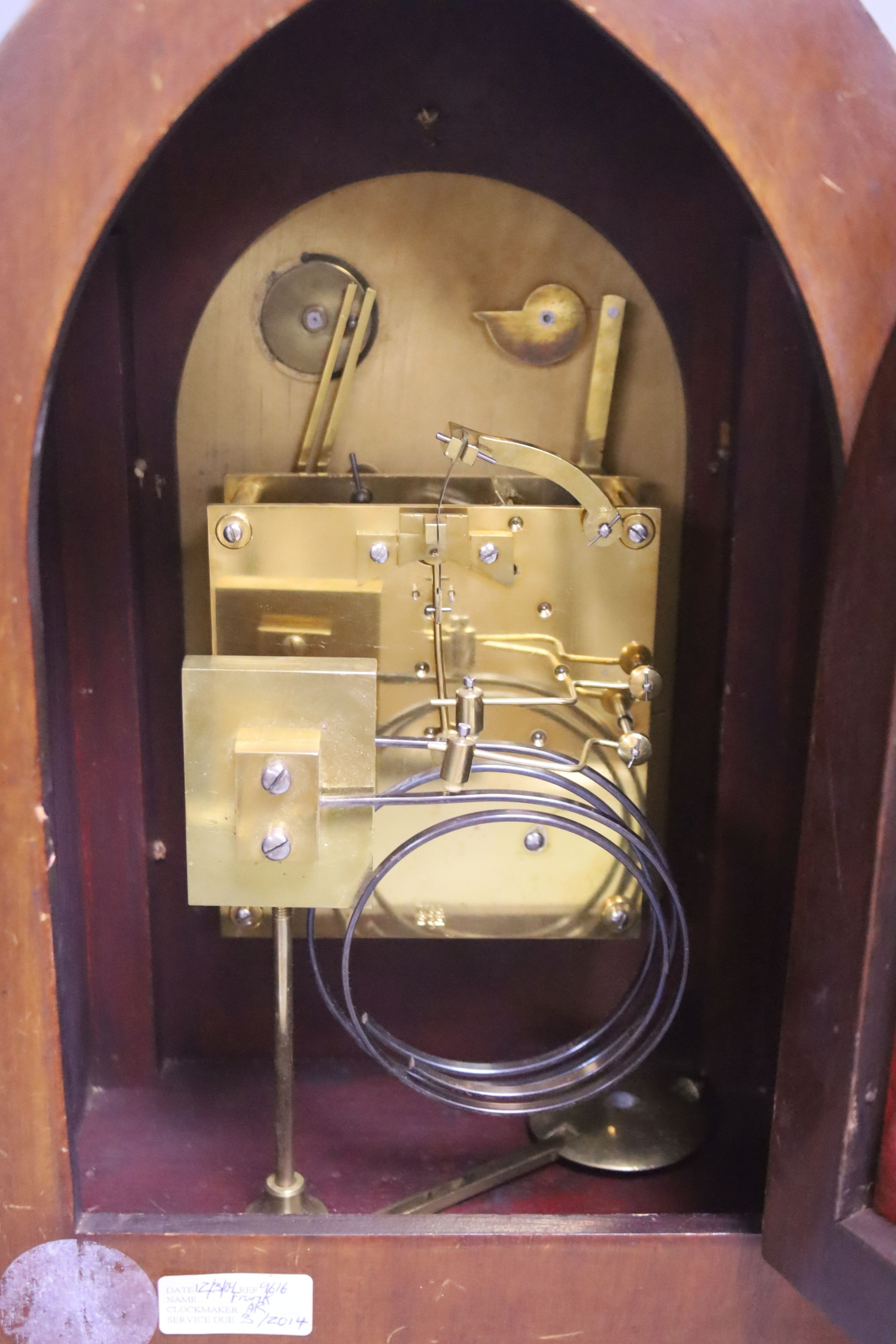 An inlaid mahogany lancet shaped chiming mantel clock with silvered dial, circa 1900. Pendulum and key. 38cm